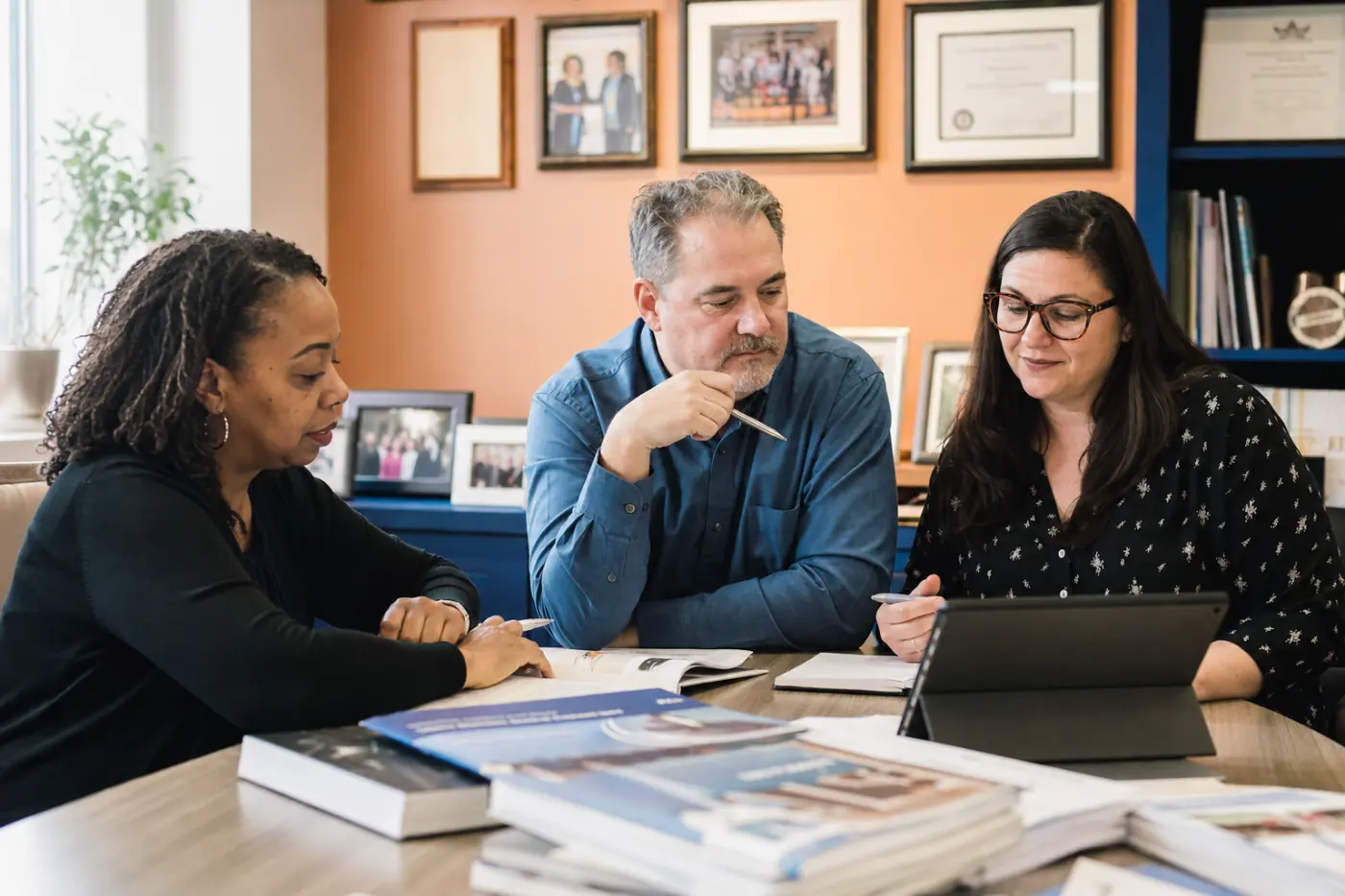 An association’s publications team with a member handbook, study guides and a tablet