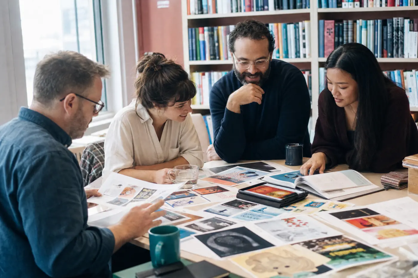 An editorial team reviewing book covers and page proofs around a table